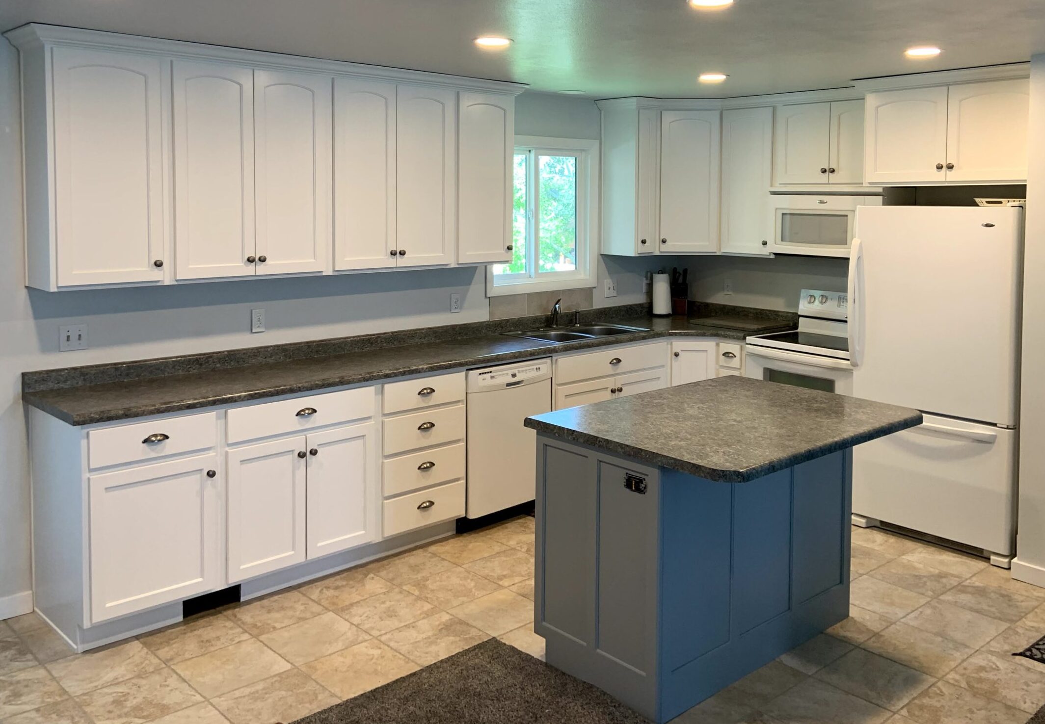 Wide angle after photo of knotty wood cabinets in satin white with new doors and drawer fronts, with an accent gray island cabinet